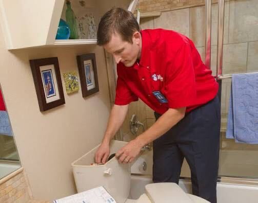 Mr. Rooter technician repairing a toilet tank